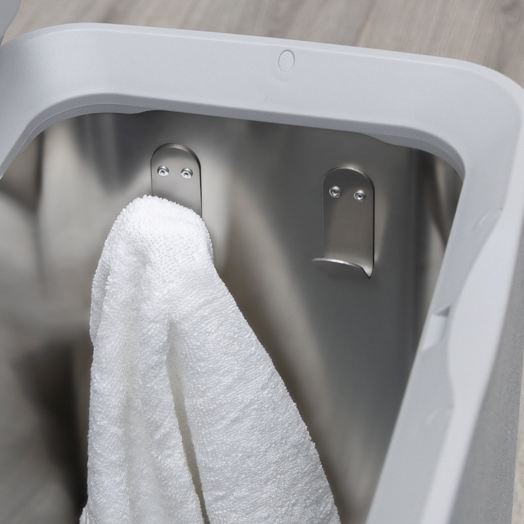 Gray towel warmers inside view showing a stainless steel tub without removable tray and with hooks and a hanging white towel over a gray wooden bathroom floor surface