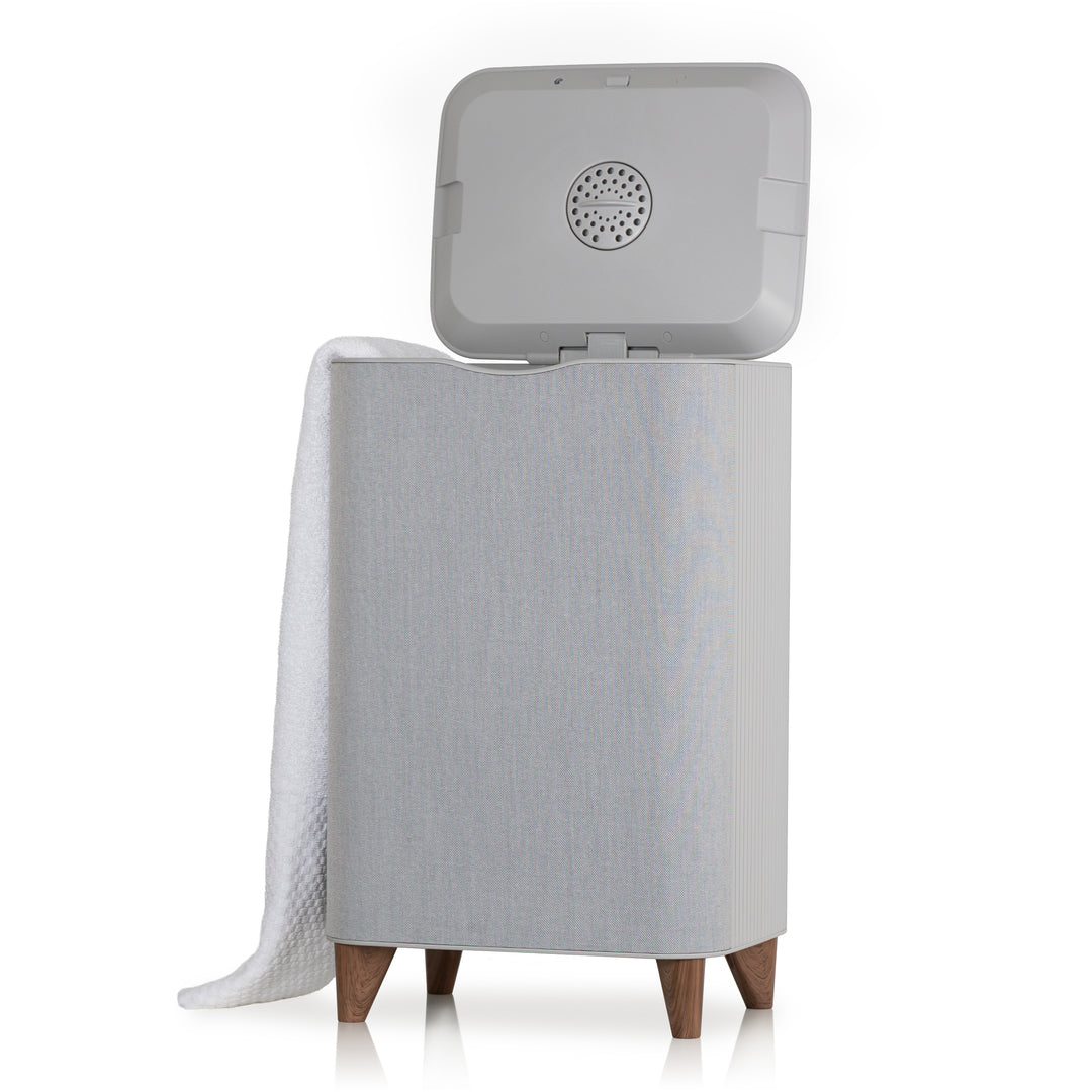 Gray towel warmer with open lid and white towel draped over back side on a white background