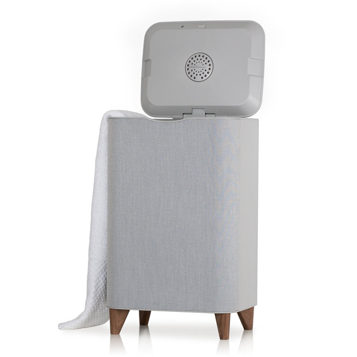 Gray towel warmer with open lid and white towel draped over back side on a white background