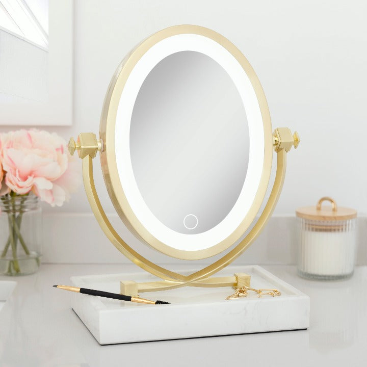 Zadro LOVGLAM55 705004424363 environment photo front left angle view with items in tray, brooklyn led lighted makeup mirror with magnification & marble trayon top of a bathroom countertop & next to a bouquet of flowers
